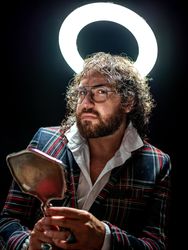 Serious man with glowing fake nimbus holding mirror and looking at camera