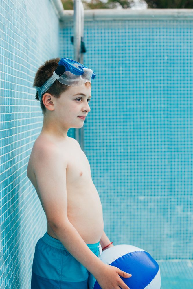 Boy with ball standing in empty pool