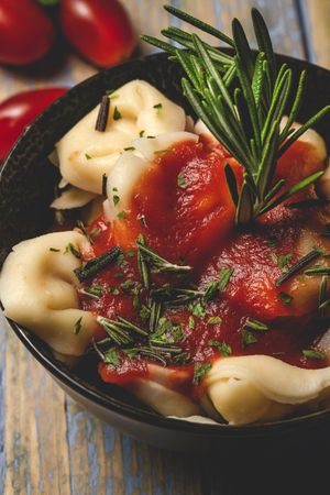 Plate of delicious ravioli with tomato sauce served on table