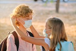 Loving sister putting mask on brother
