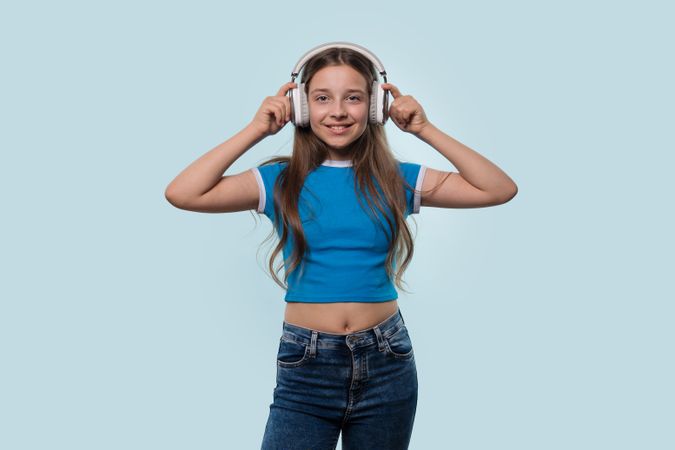 Girl in blue t-shirt smiling while wearing headphones.