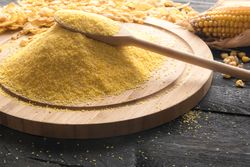 Pile of polenta on a wooden board on dark wooden background