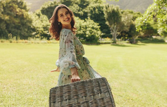 Beautiful woman with picnic basket walking in the park