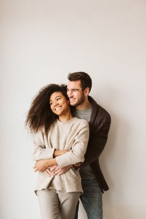 Young multiracial couple hugging and looking away