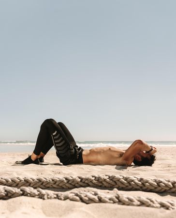 Tired man lying on the beach after doing fitness workout on a sunny day