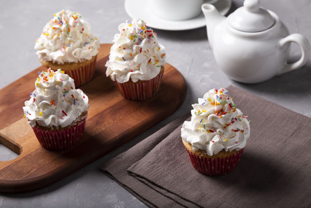 Tasty party cupcakes on the table. Cupcakes with whipped cream.