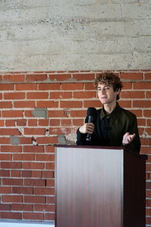 Person public speaking with a microphone at a podium