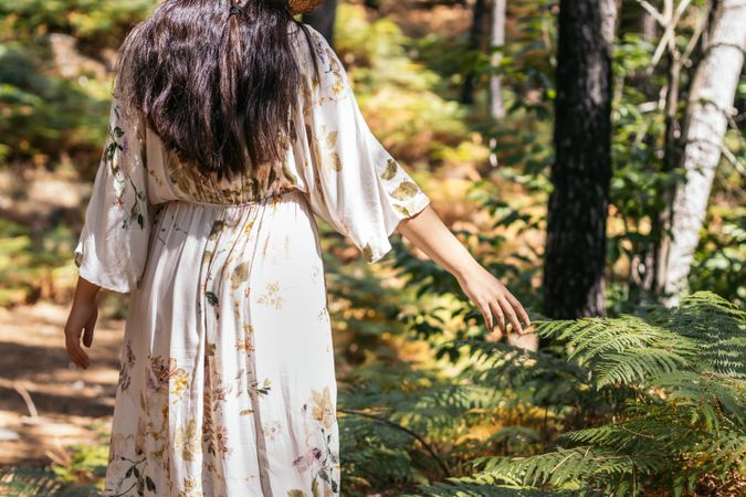 Young woman touching leaves in the forest