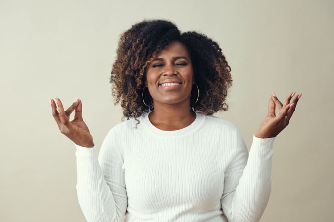 Portrait of smiling Black woman with her hands up in meditation