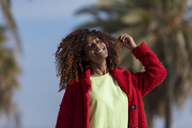 Female with curly hair smiling with the sunshine on her face