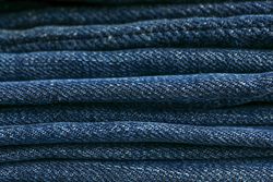 Stack of blue jeans as background, space for text