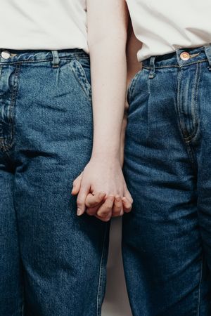 Two people in blue denim jeans holding hands