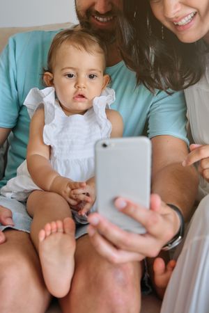 Crop parents with girl using smartphone