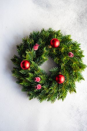 Holiday wreath with red baubles and berries on marble counter