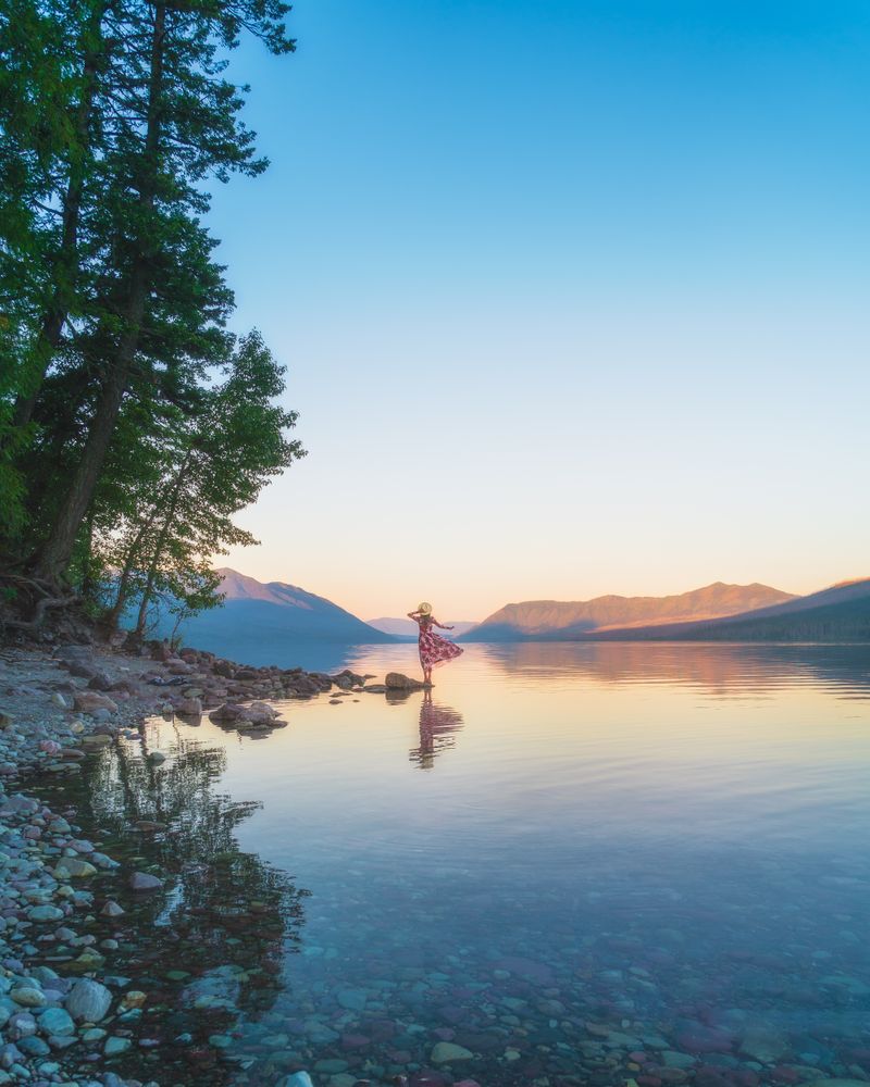 Woman wearing dress standing on rock near lake