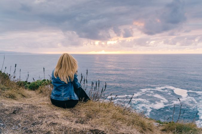 Woman on seashore against dusky clouds