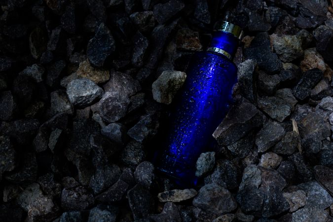 Wet blue perfume bottle mock up laying in rocks