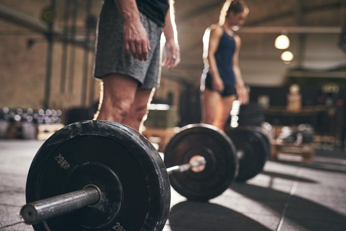 Close up of weight plate with athletes in the background
