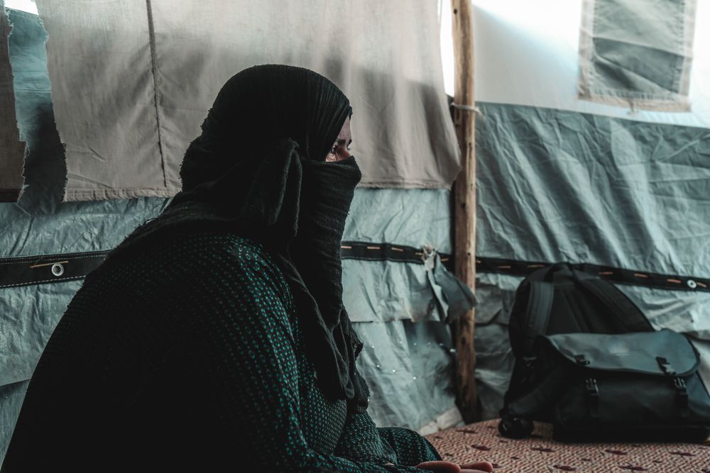 Woman in a hijab crying and sitting in a tent