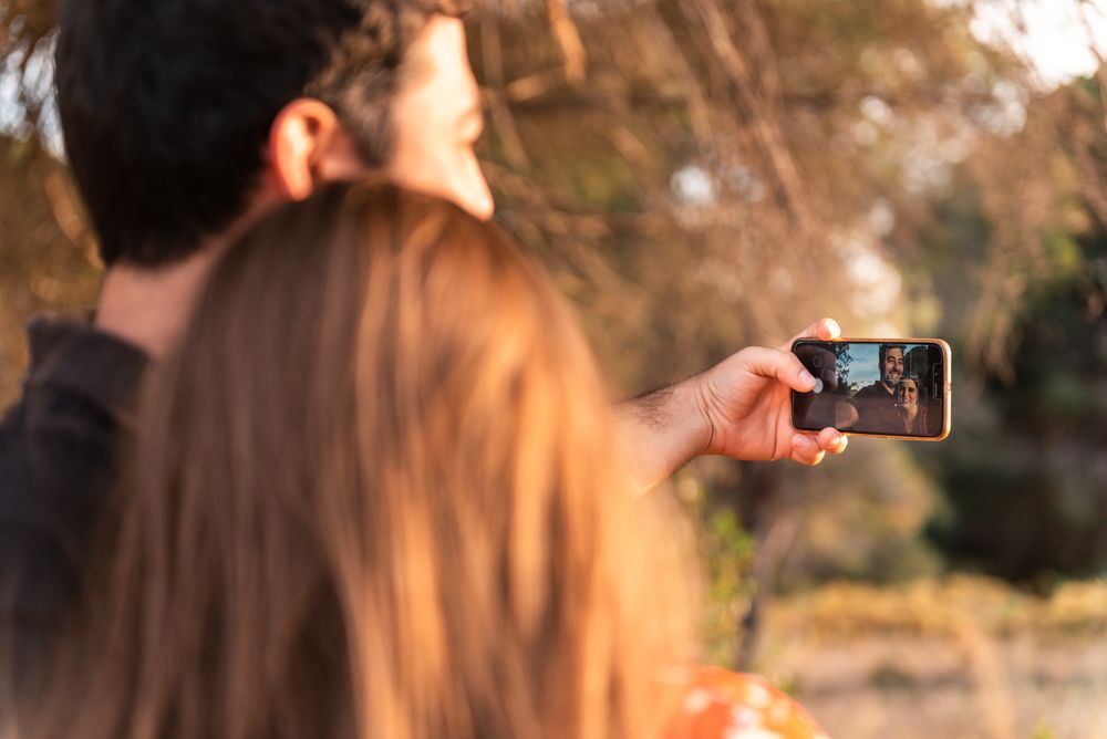Couple kissing and taking photo outdoors