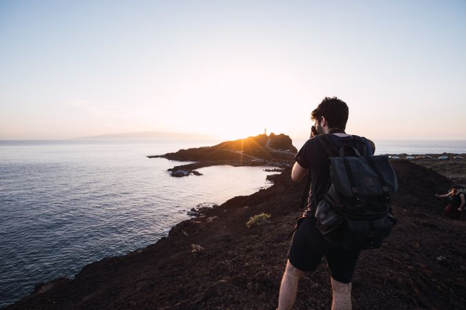 Photographer picturing sunset above remote coast