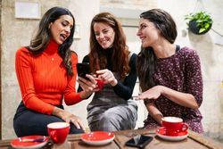 Female friends smiling at something on a friend’s smartphone
