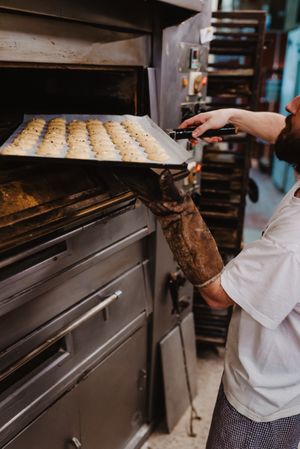 Bald baker checking pastry inside oven