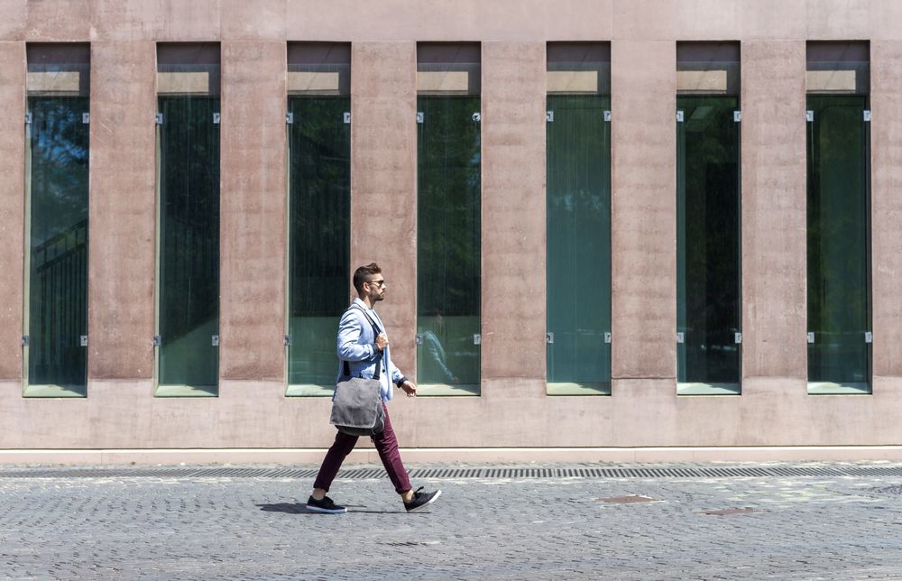 Side view of young trendy professional walking in street wearing smart casual jacket