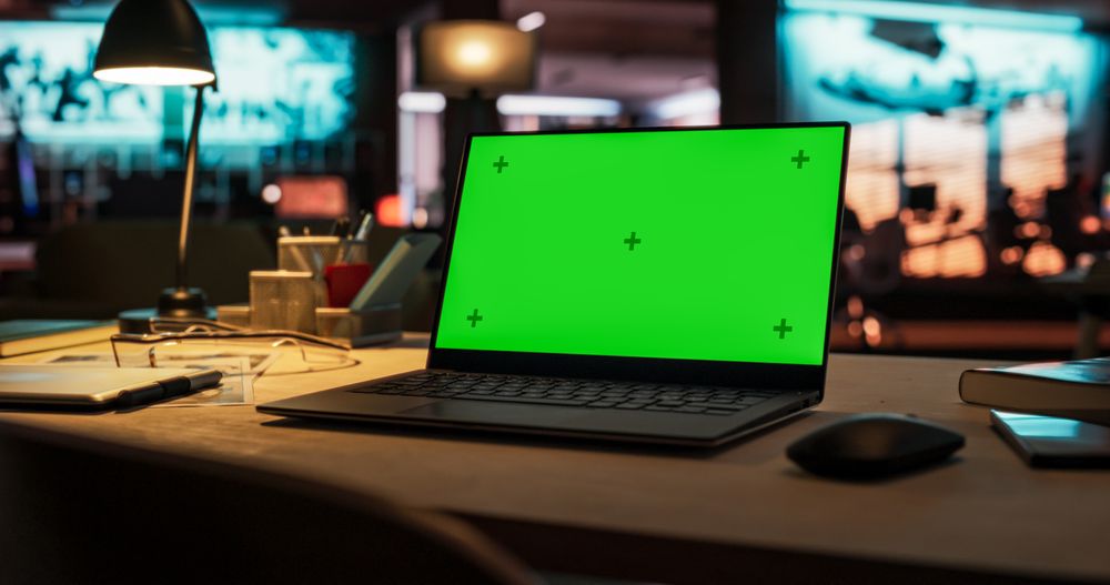 Laptop Computer Standing on a Wooden Desk with a Green Screen Chromakey Mock Up Display. Creative Office and Working Environment Boosting Creativity and Innovative Ideas