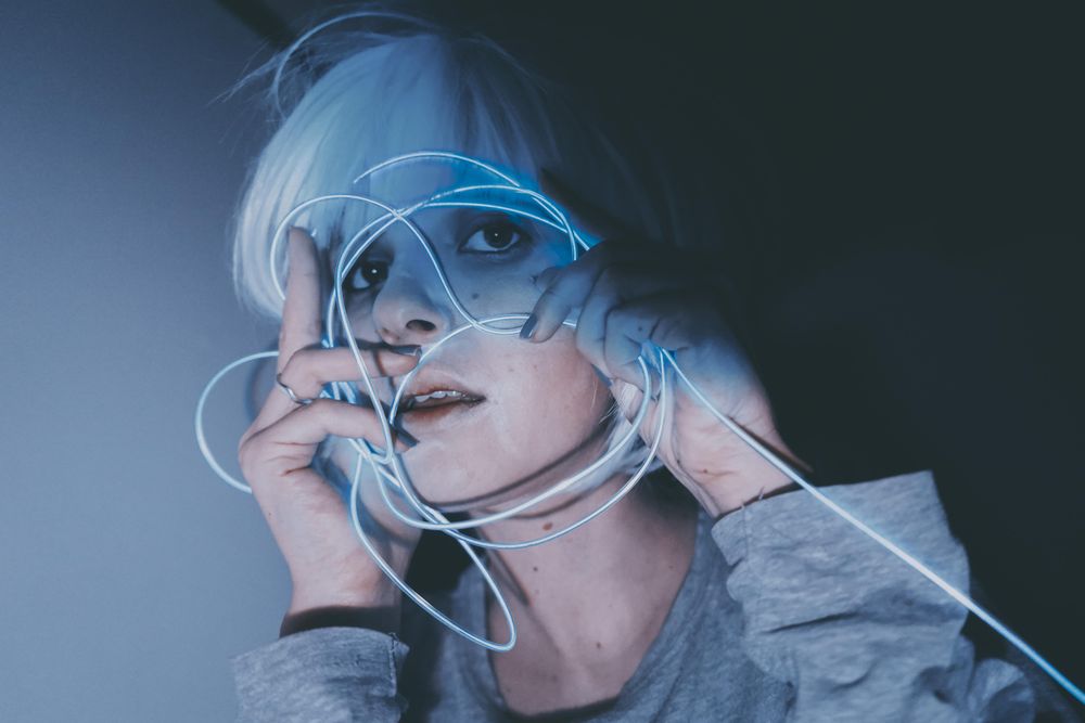 Portrait of woman in gray shirt holding blue led light thread