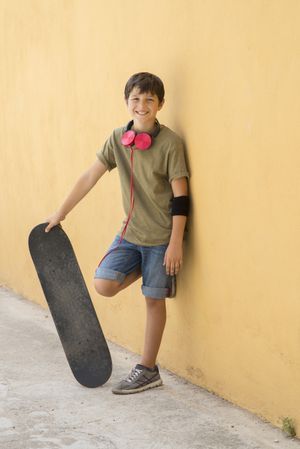 A Teen with skateboard standing on city street