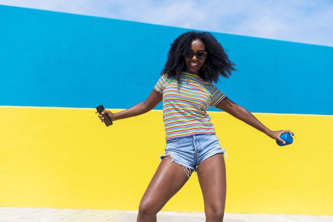 Black woman dancing in front of bright yellow and blue wall