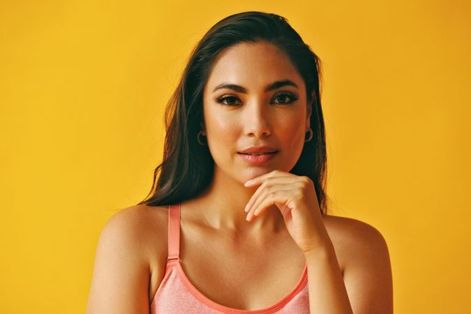 Headshot of Hispanic woman with hand to her chin in front of a yellow background