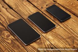 Three phones of different sizes on wooden table 0VKeN5