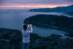 Solo man on coastal cliff as the sun goes down