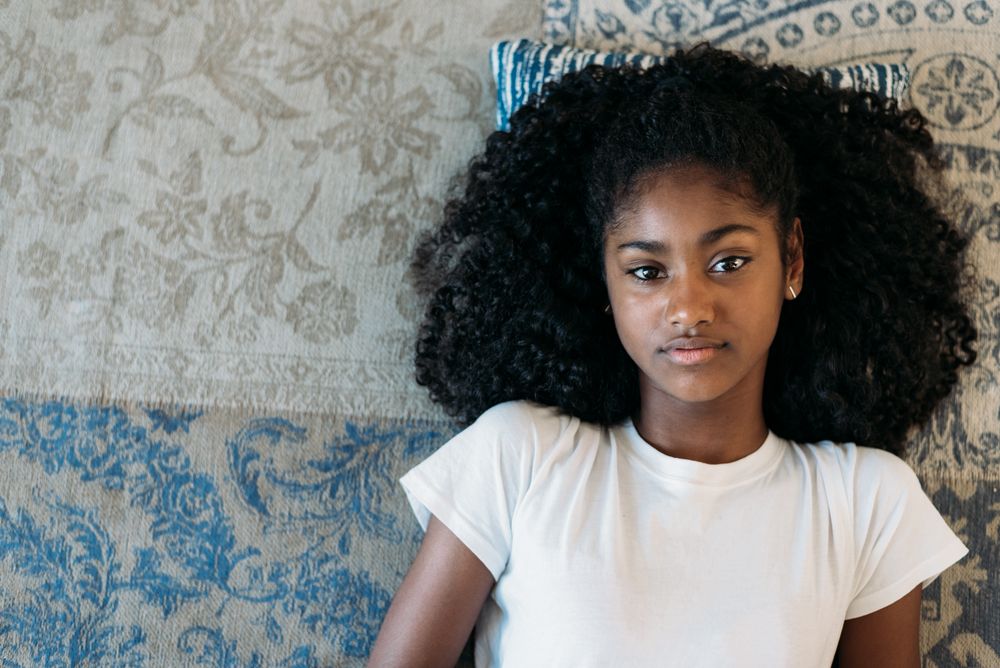Beautiful young Black teenage girl lying down in a rug