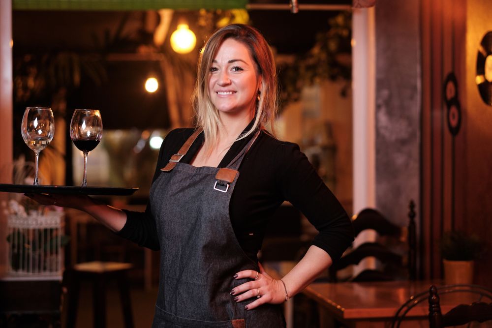 Cheerful waitress holding tray with wineglasses