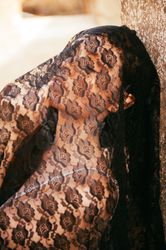 Woman leaning back on wall with lace material covering her head and shoulders