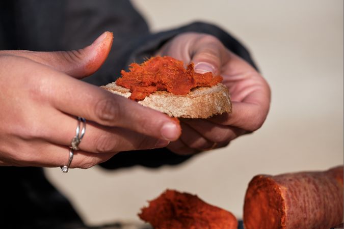 Crop person making sandwich with chorizo