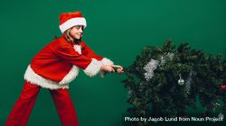 Girl dressed as Santa Claus taking down a Christmas tree 4NPOm0