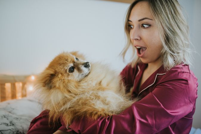 Smiling woman sitting in bed with dog