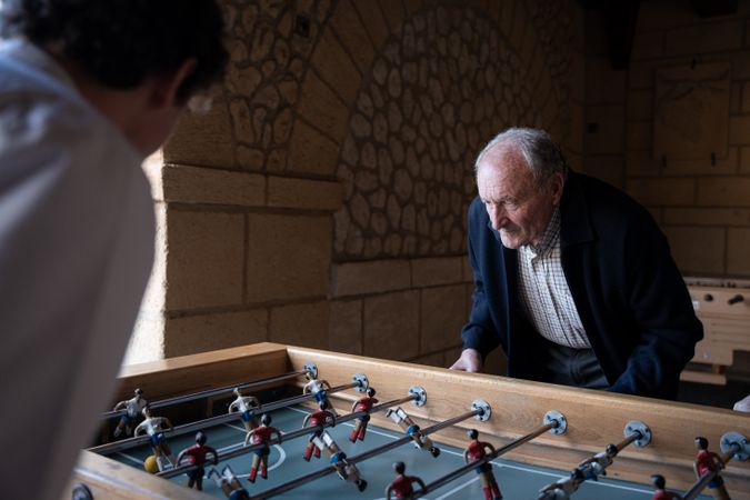 An old man is playing table football with his family
