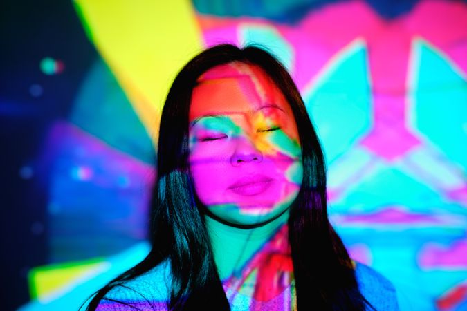 Peaceful Asian woman under multicolored lights