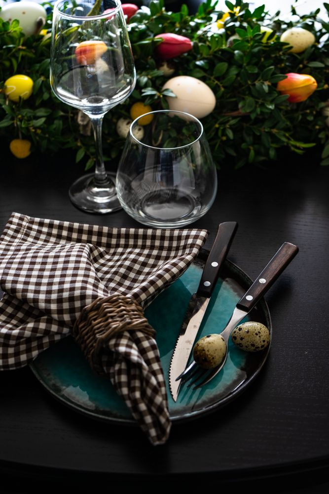 Easter table setting with delicate spotted eggs on ceramic teal plate and tulip centerpiece