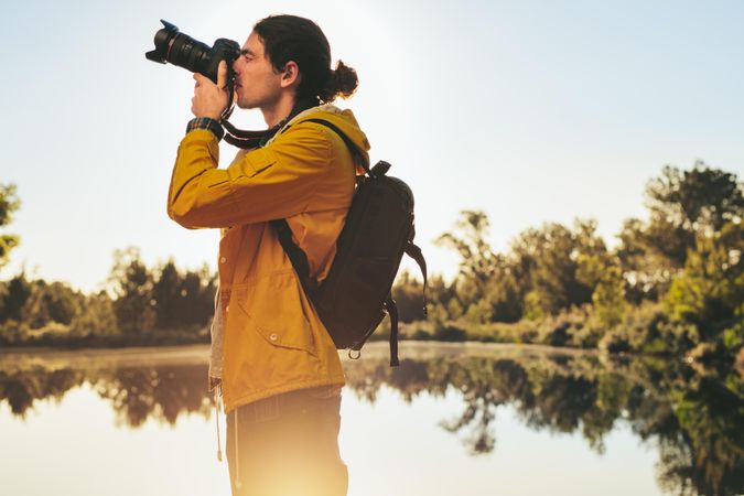 Young man capturing the beauty of nature standing near a lake