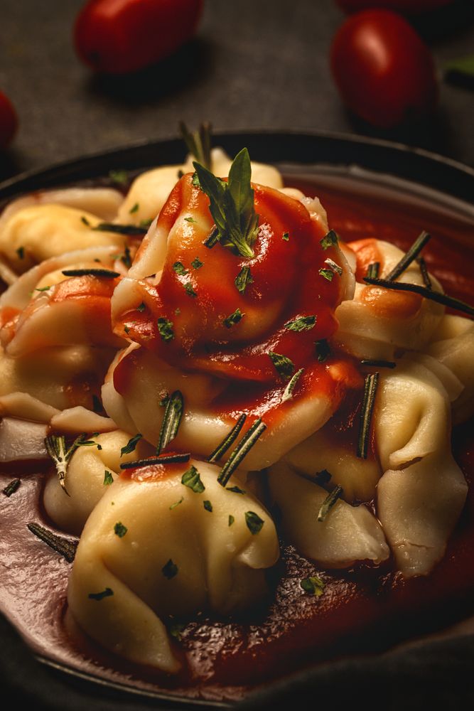 Plate of delicious ravioli with tomato sauce served on table