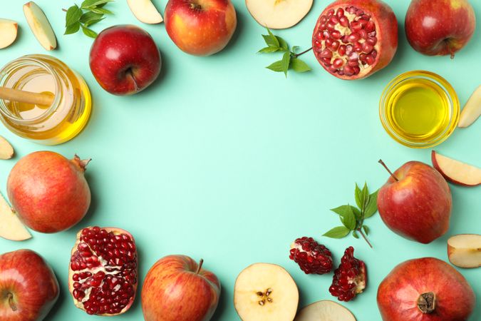 Top view of arrangements of apples, honey, pomegranate on mint green table