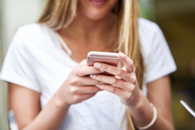 Hands of blonde female typing text message on cellphone