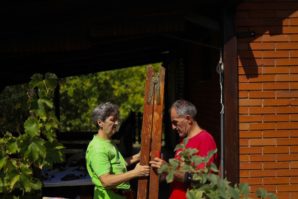 Older couple carrying the ladder together.