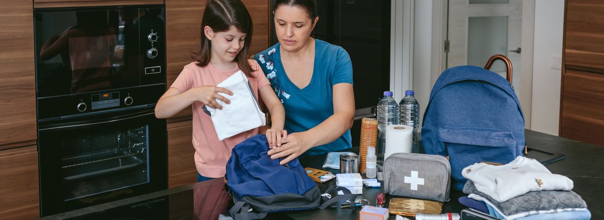 Mother preparing emergency backpack with her daughter